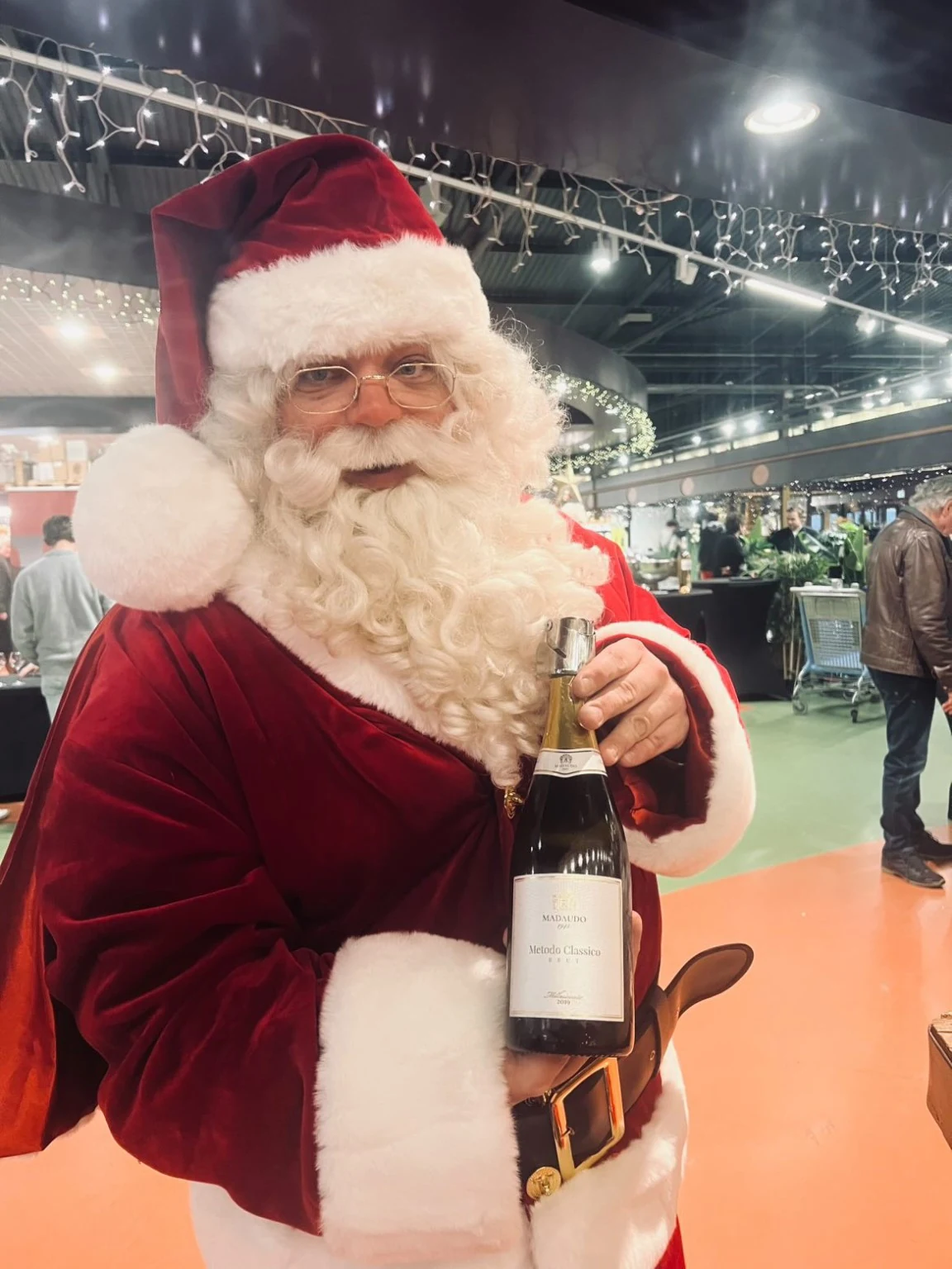 Kerstman met een fles mousserende wijn tijdens een evenement
