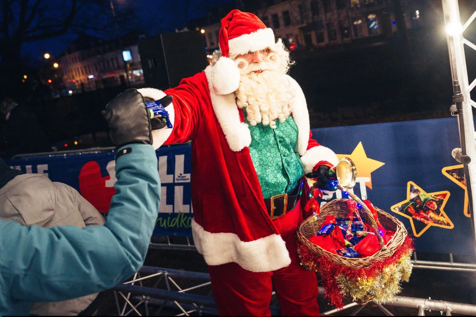 Kerstman deelt iets uit aan een bezoeker bij een winterevent