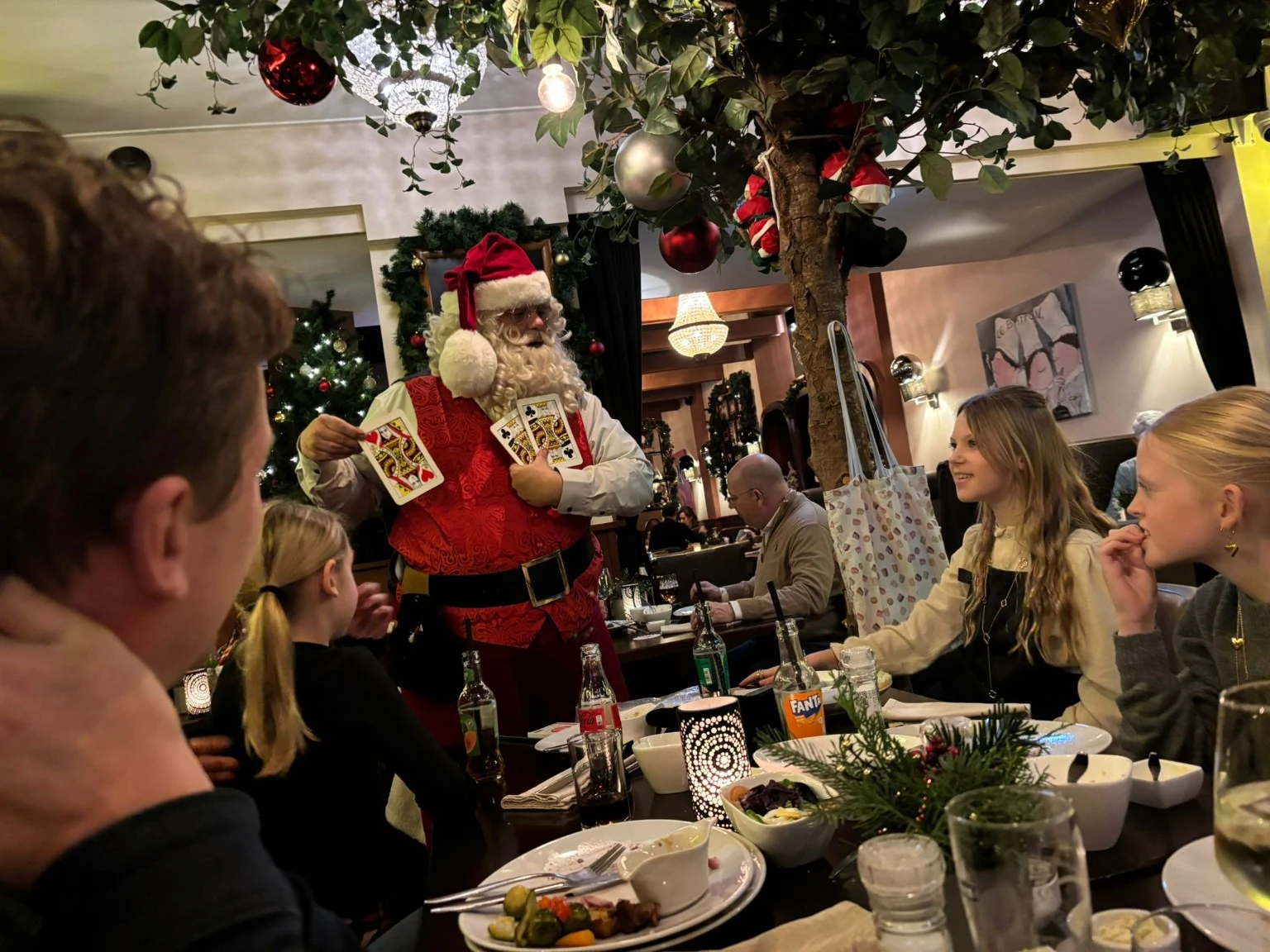 Kerstman doet kaartmagie aan tafel in een restaurant