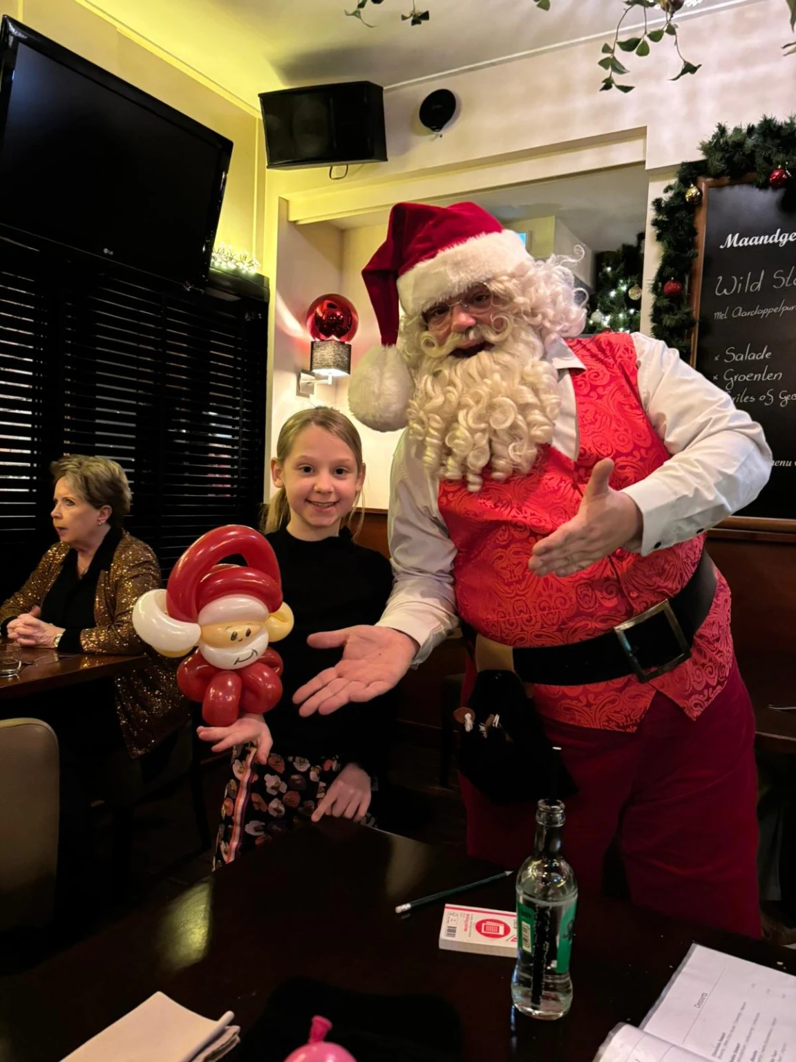 Kerstman met kind en ballonfiguur in een restaurant