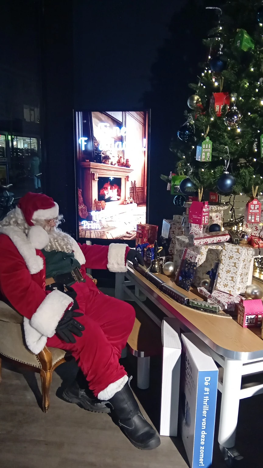 Kerstman bij kerstboom en cadeaus in een winkel